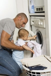 photo of man teaching his son to do laundry