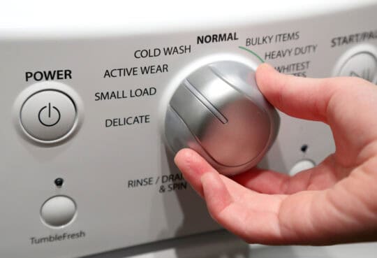 hand turning the dial on a washing machine